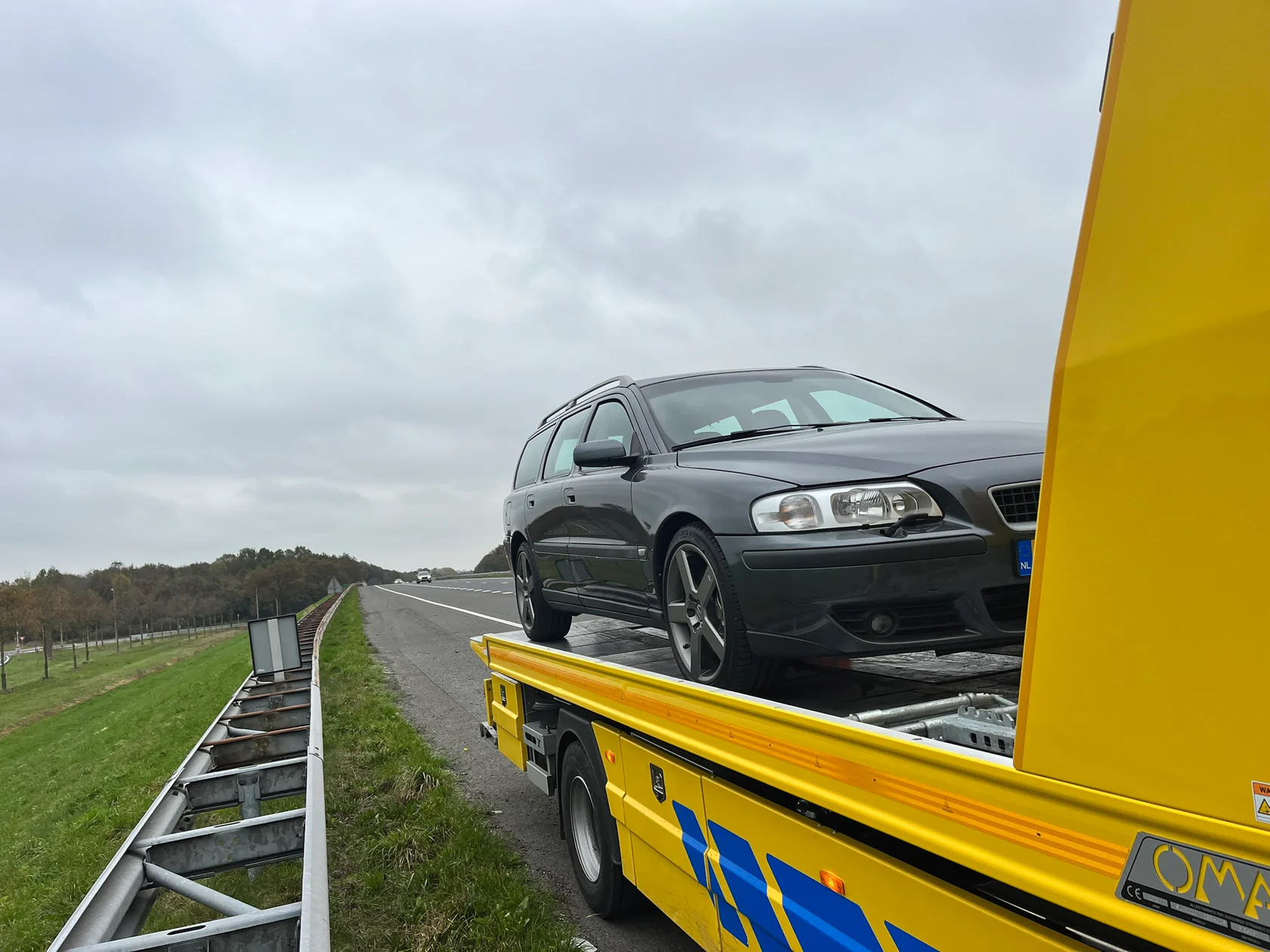 Grijze Volvo V70R op een gele autoambulance langs de snelweg