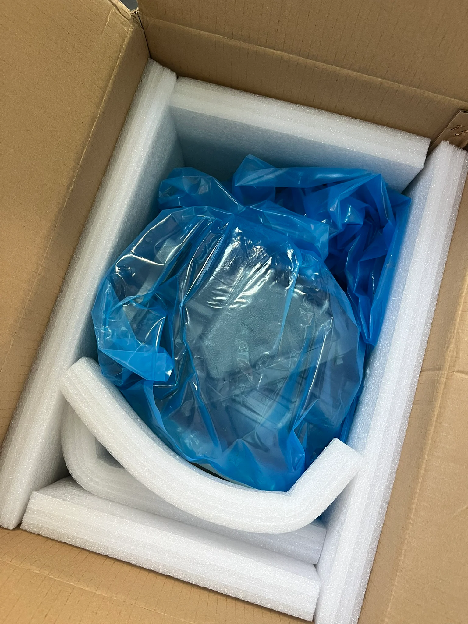 Haakse overbrenging in blauw plastic, omringd door wit schuim in een kartonnen doos